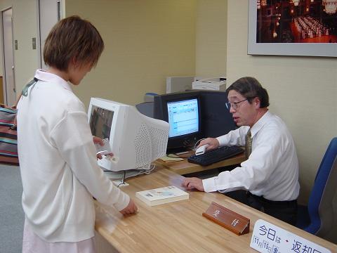 「あすなろ図書館」で本の貸し出し手続きを行う専任司書の菊池佑さん